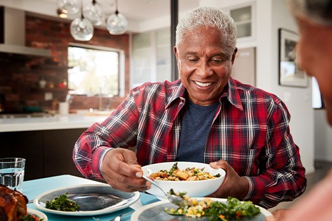 Senior man filling plate at table