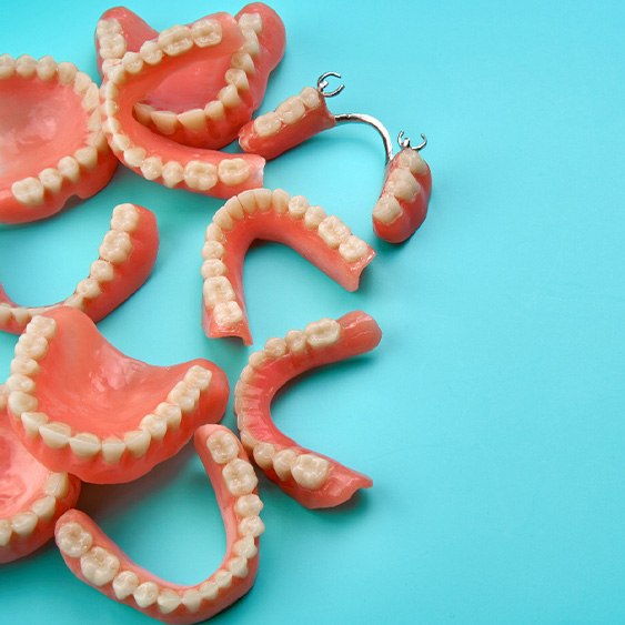 Multiple sets of dentures crowded together on light blue background
