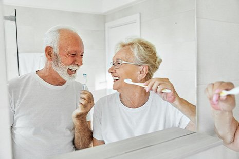Senior couple smiling while brushing their teeth