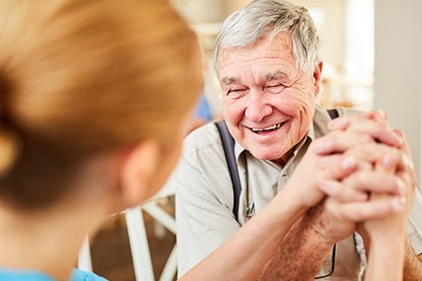 Dentist in Abilene holding smiling older patient’s hand  