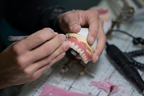 Hands carving wax gumline of dentures