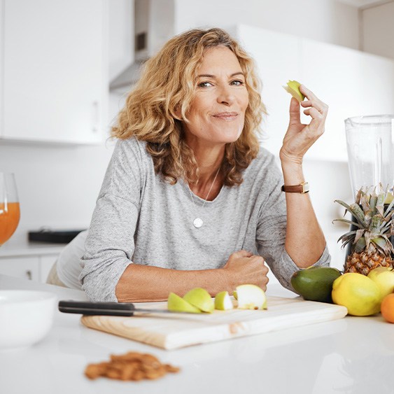 Woman smiling while enjoying snack in kitchen