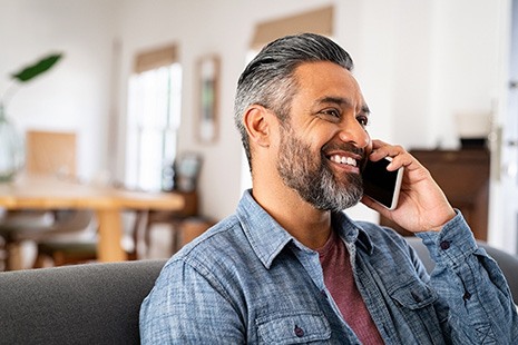 Man smiling while talking on phone at home