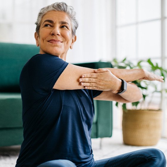 Senior woman smiling while stretching at home