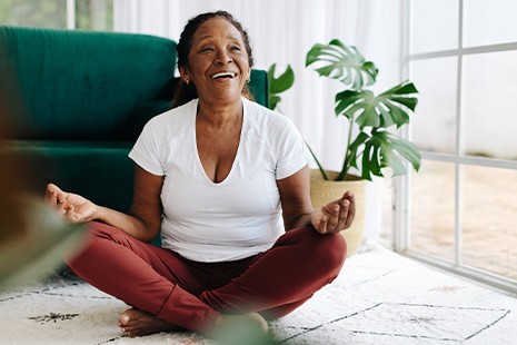 Senior woman smiling while meditating at home