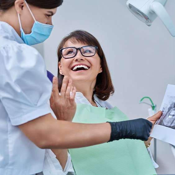 Dentist reviewing X-ray with smiling patient