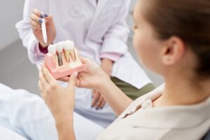 Patient holding model of dental implant while dentist explains.